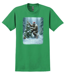Bigfoot Christmas T-Shirt Lonely Sasquatch Decorating a Christmas Tree Wearing a Santa Hat in a Forest With Snow