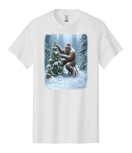 Bigfoot Christmas T-Shirt Lonely Sasquatch Decorating a Christmas Tree Wearing a Santa Hat in a Forest With Snow
